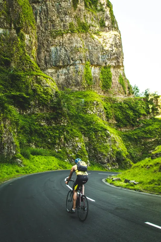 Cyclist on a winding road under a cliff